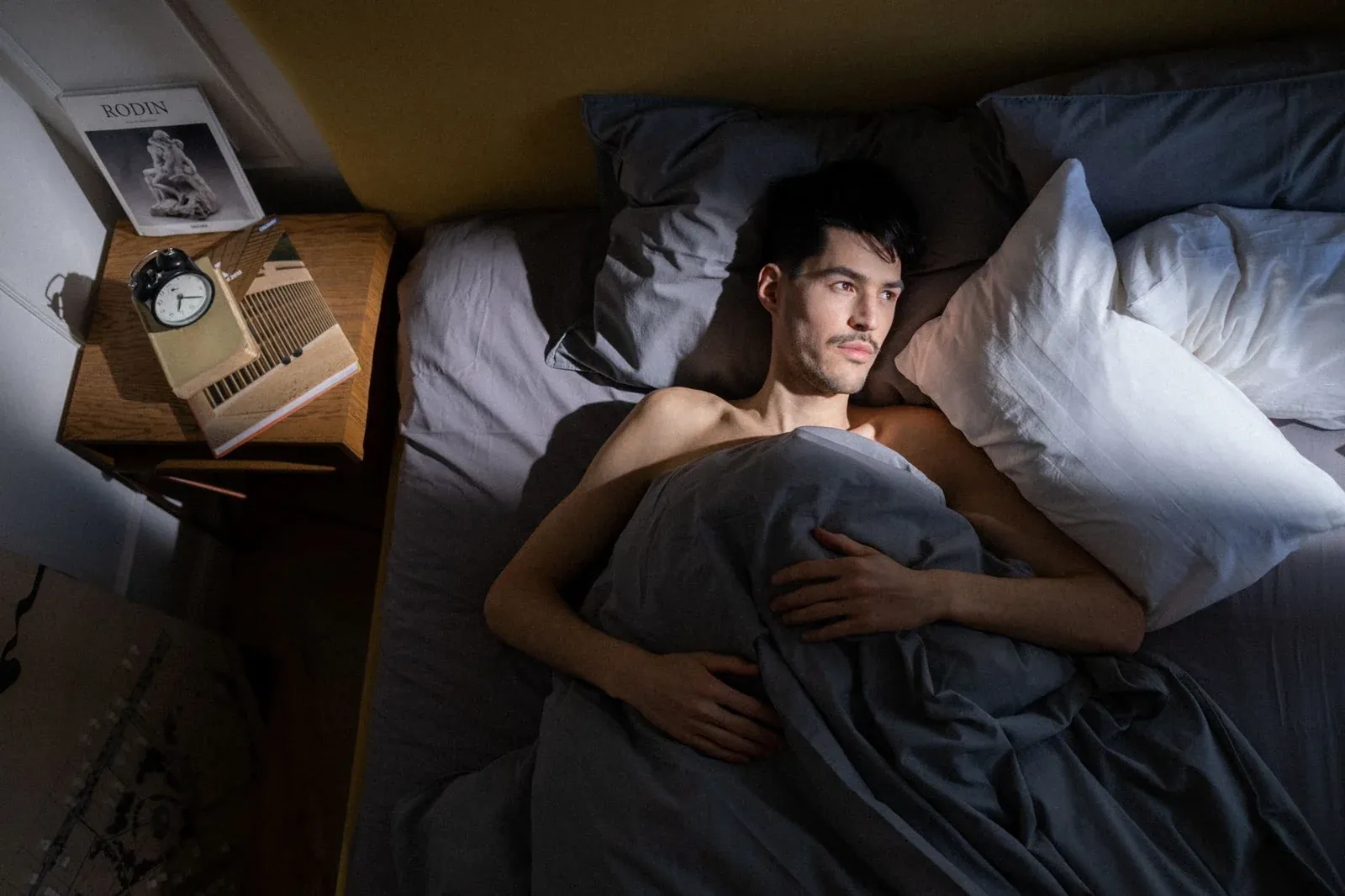 Un homme allongé éveillé dans son lit la nuit, en proie à des troubles du sommeil